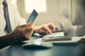 Man using a credit card to pay bills inside an office Man using a credit card to pay bills inside an office